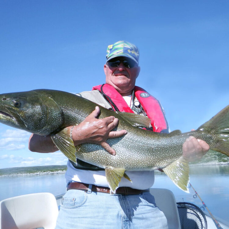 Angler holding a monster lake trout sunny calm sunny day