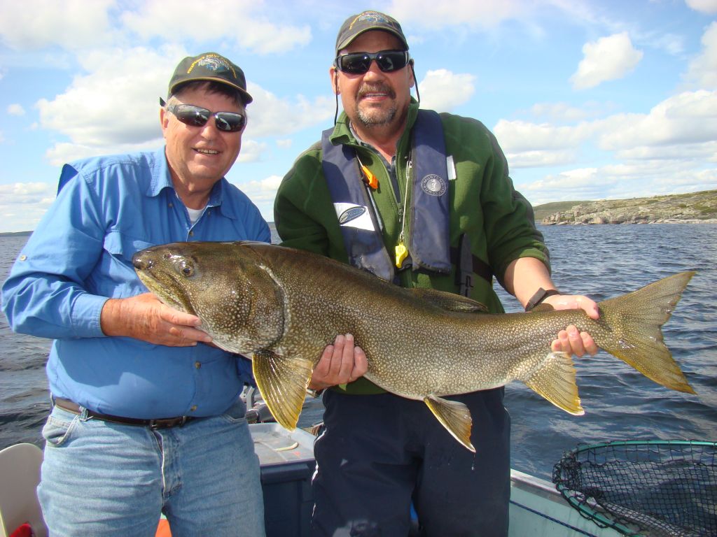 Two men in boat holding a trophy lake trout on a warm summer day