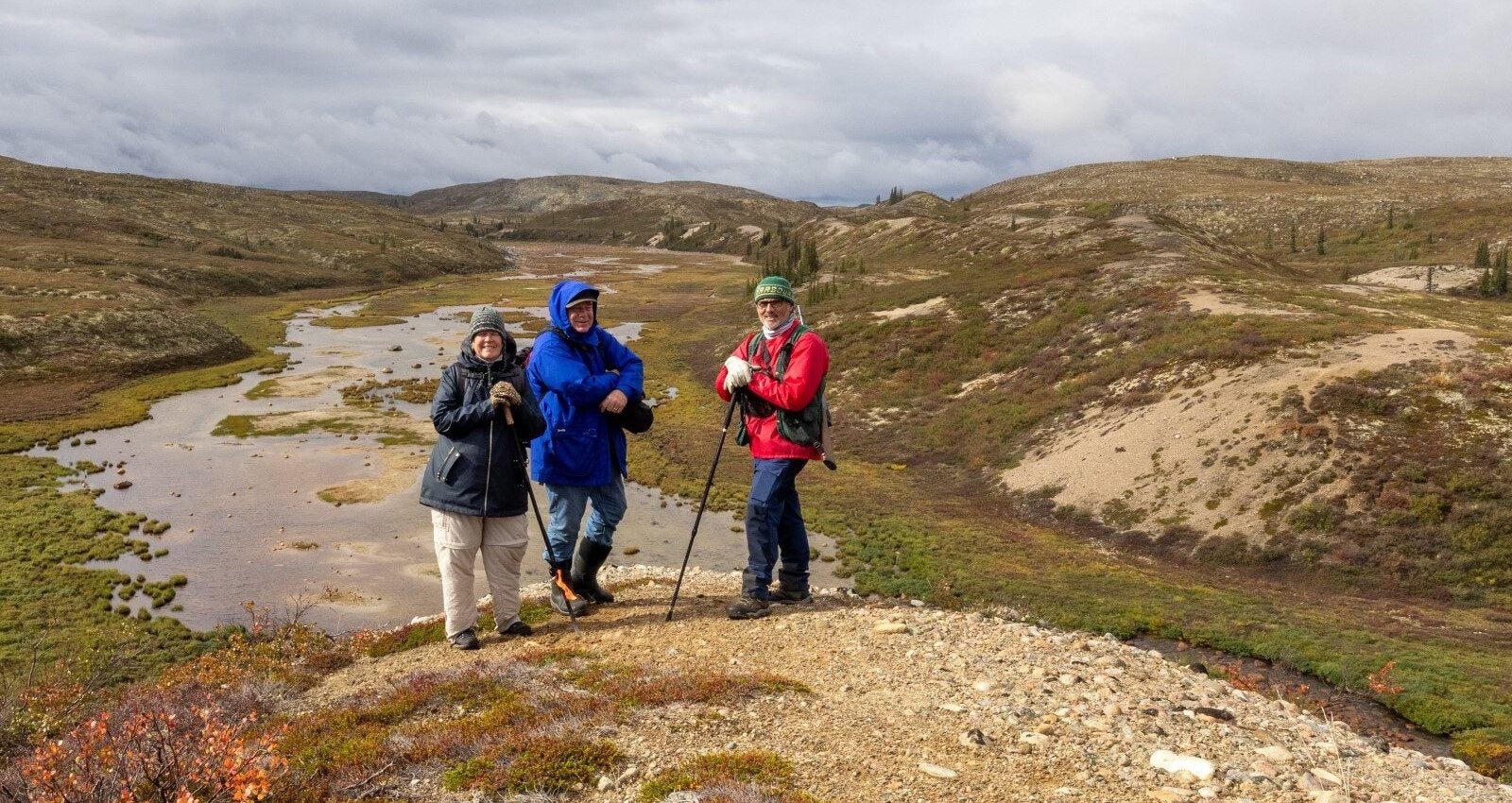 Three people pose for a photo on the crest of an esker in Canadian Barrenlands