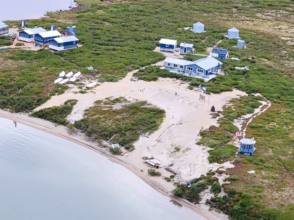 Aerial view of a lodge on tundra in summer with guest cabins and gazebo
