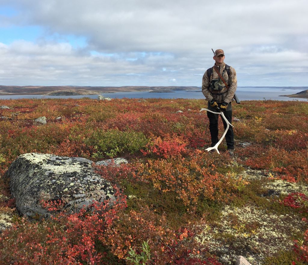 Man on the barrenlands with caribou antler shed and rifle on his back. Bear monitor 