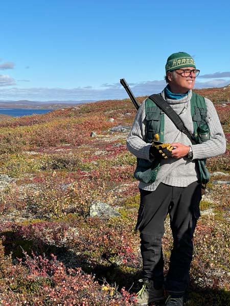 Man with rifle slung over his shoulder overlooking the great Canadian barrenlands