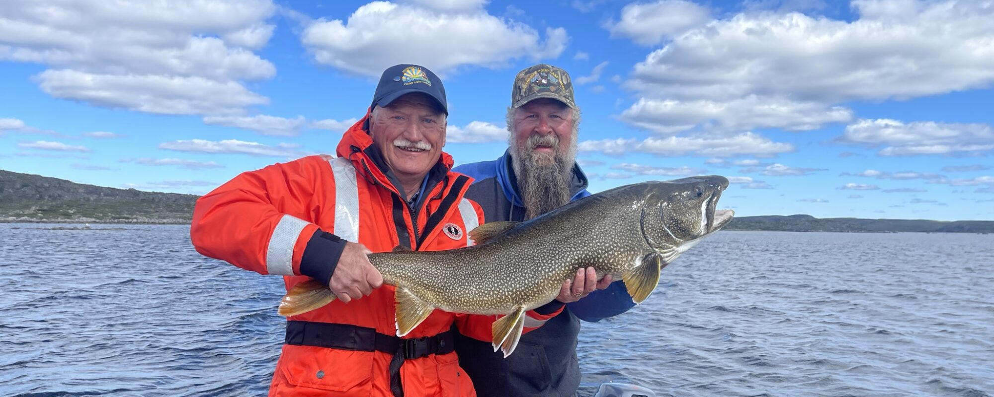 Two men in boat on summer day holding trophy lake trout