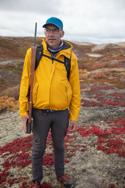 Man in Yellow jacket carrying a rifle in the autumn on the barrens