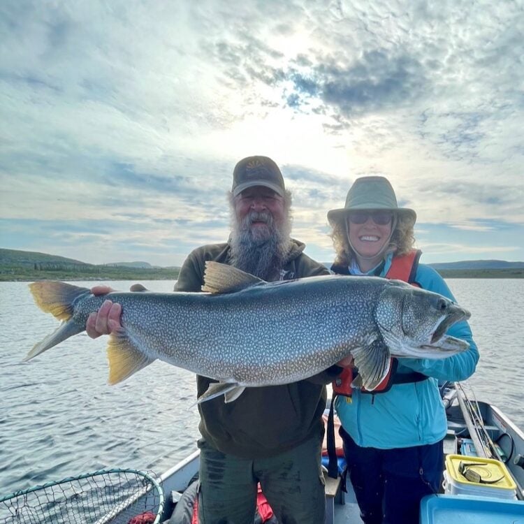 Fishing Guide and guest holding a huge lake trout on a beautiful summer