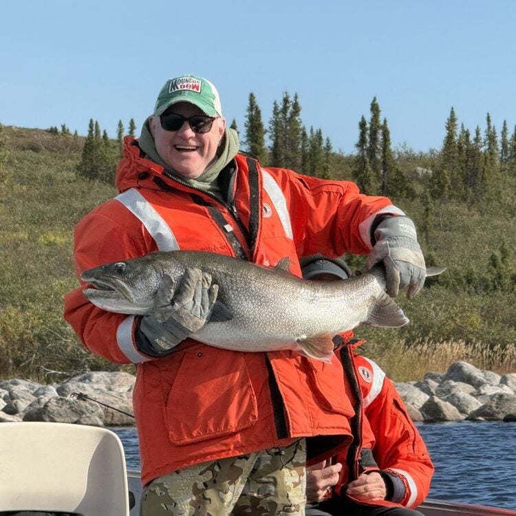 Angler holding a trophy lake trout caught during a guided fishing trip at an NWT fishing lodge - Peterson's