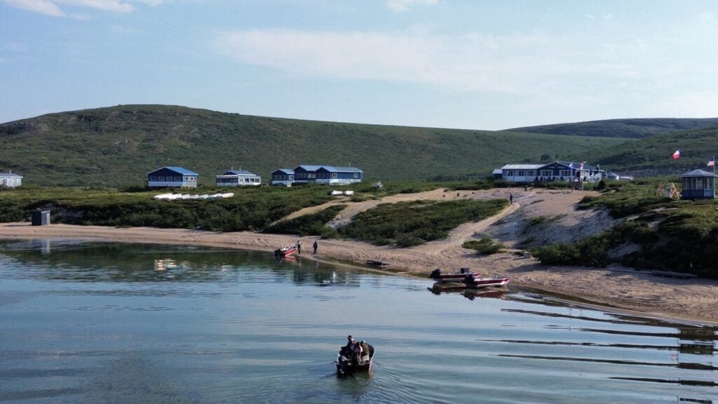 Fishing Lodge, Boats in water and on beach people ready to head out fishing on a beautiful summer day