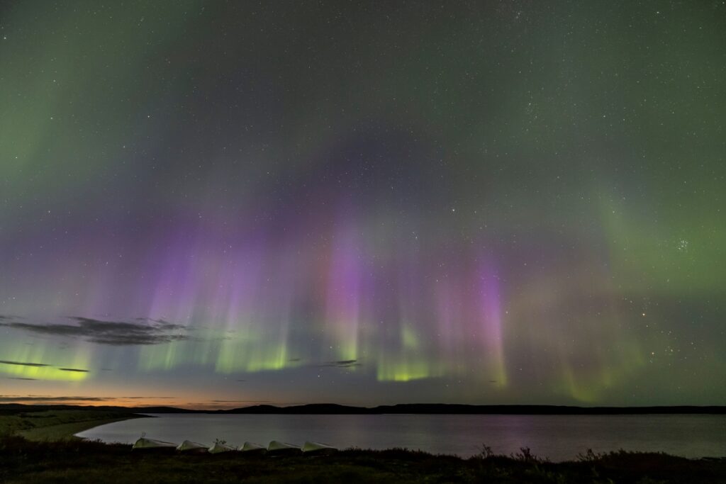 Colorful northern lights over lake with boats in foreground