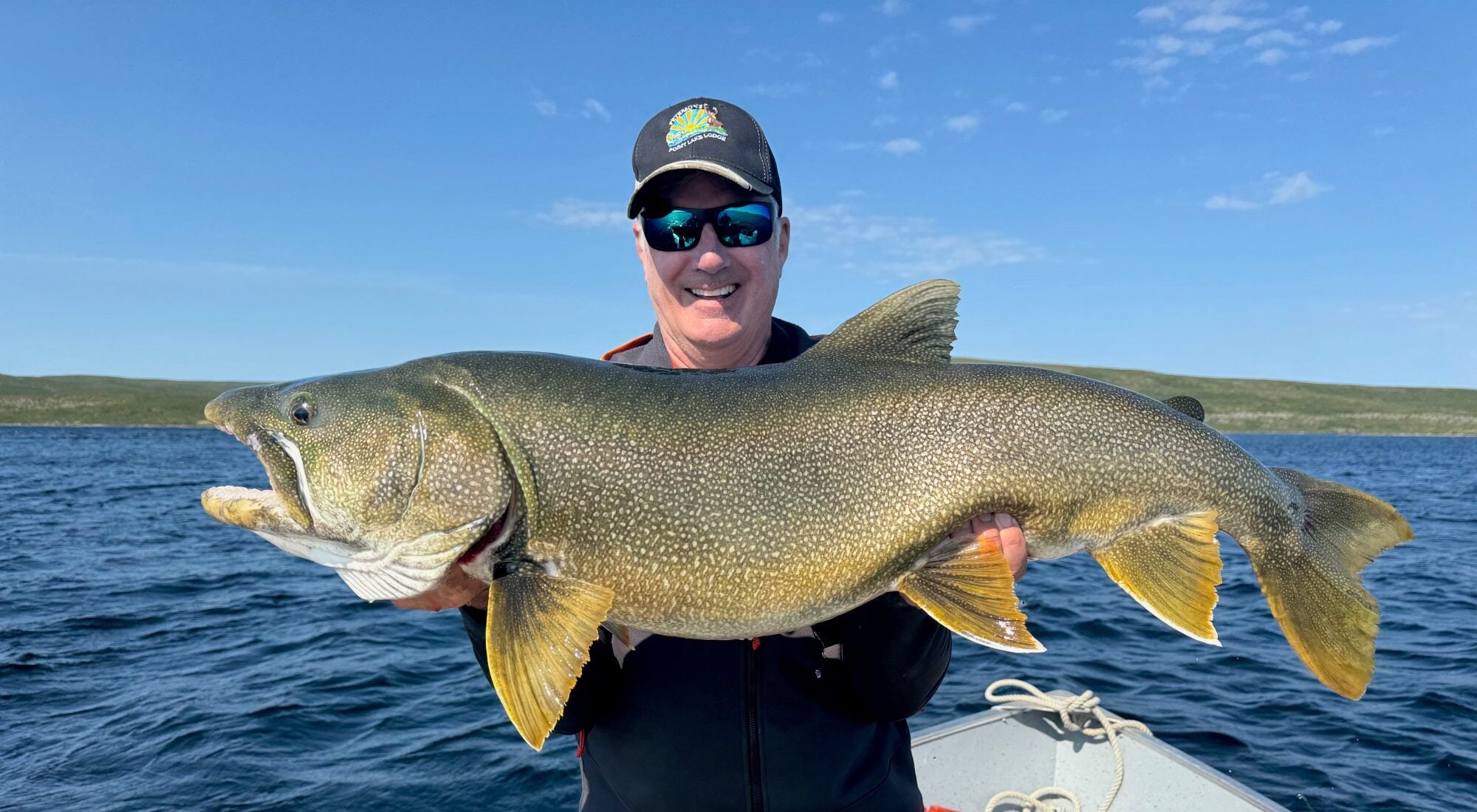 Man holding a huge lake trout on a beautiful summer day