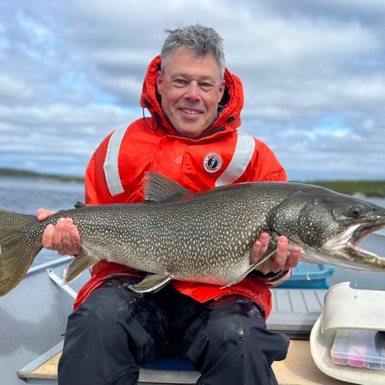 Man smiling holding a huge lake trout
