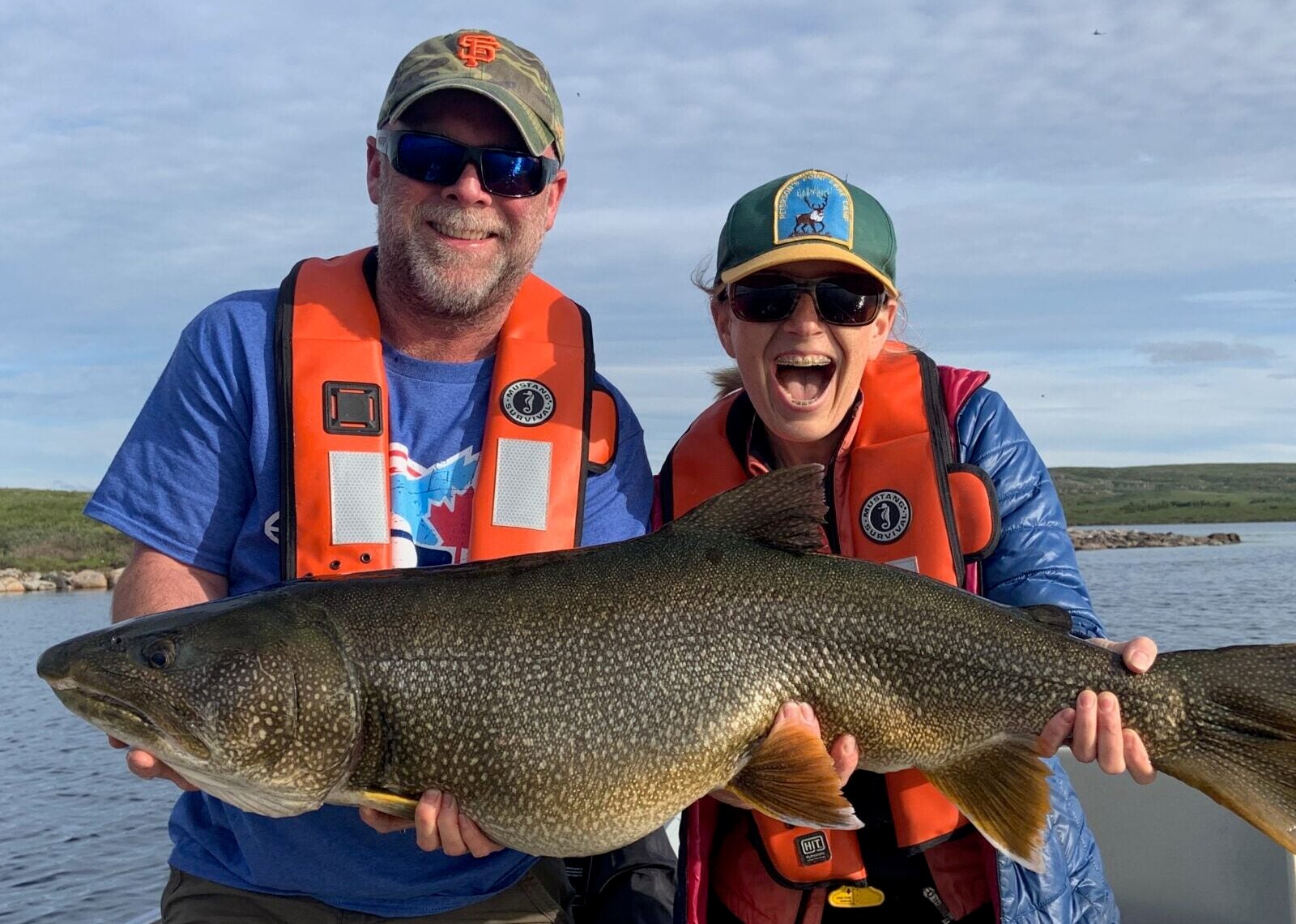 Two anglers having a blast holding monster lake trout catch